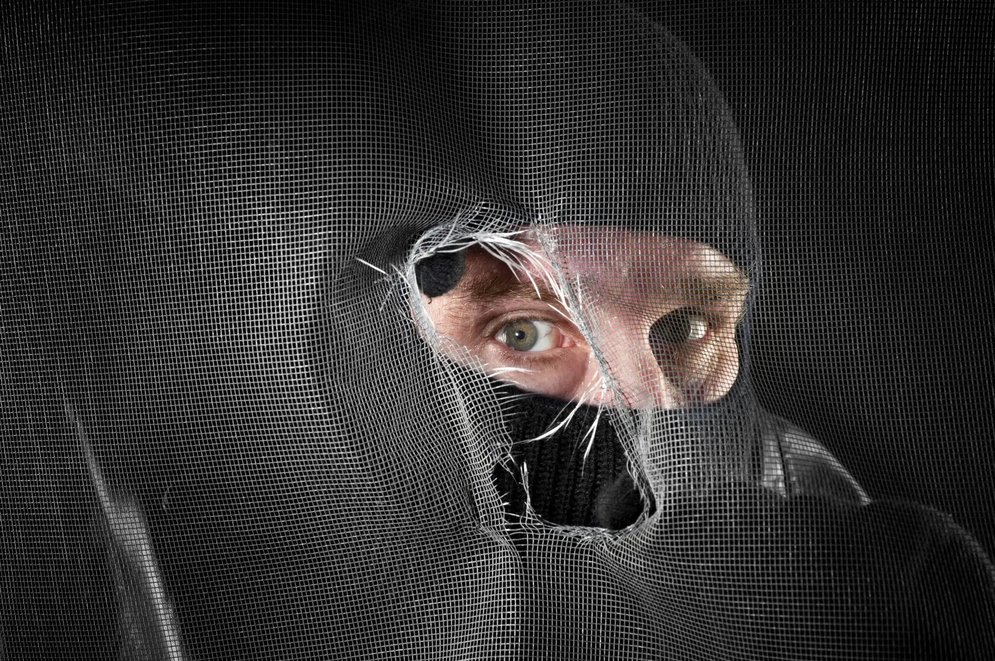 Eyes peering through torn black mask